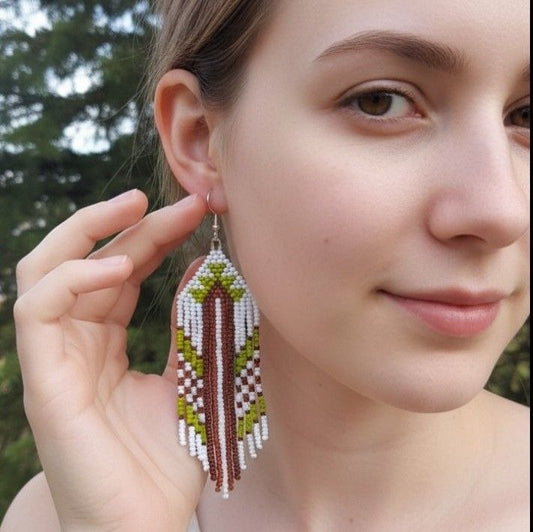 Close-up of a woman wearing colorful beaded earrings with a blurred natural background